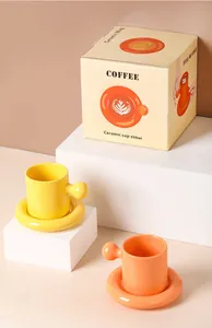Minimalist ceramic mug and saucer set with round ball handle in yellow and orange finish