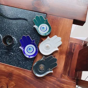 Dettaglio dei vassoi Hamsa in ceramica con bordi dorati e motivi a occhio in quattro colori