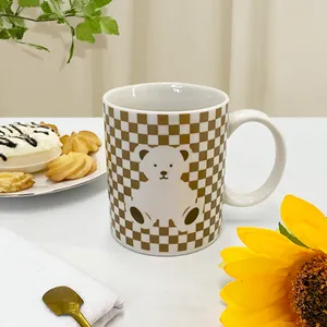 Detail shot of a checkered ceramic mug with a cute white bear illustration and handle