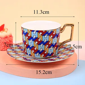 Macro view of British-style ceramic coffee cup with golden geometric handle and H-pattern