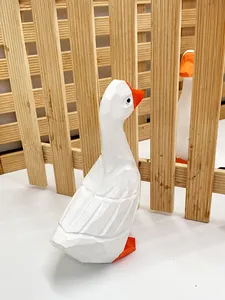 Détail de figurines canards blancs géométriques en résine sur fond de clôture en bois