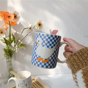 Close-up of blue checkerboard ceramic mug with cartoon duck and matching spoon