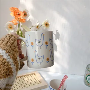 Close-up of a white ceramic mug with blue bird and orange sunflower patterns with a spoon
