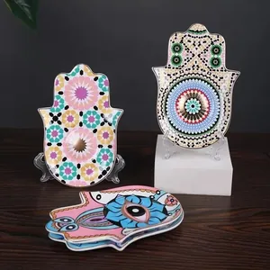 Hamsa Hand ceramic jewelry tray with Evil Eye patterns and gold trim on wooden desk