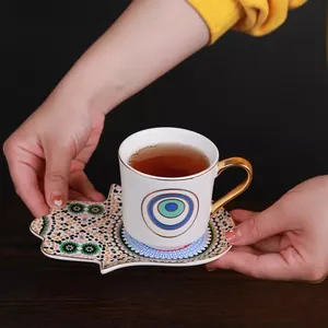 European gold-rimmed ceramic coffee cup with Hamsa-shaped tray and mosaic patterns