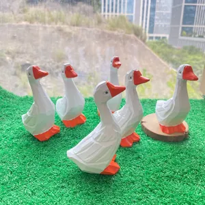 Vue détaillée de six figurines de canards blancs géométriques sur gazon synthétique vert