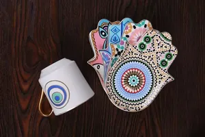 Detailed top view of white ceramic coffee cup with Hamsa Hand pattern colorful saucers