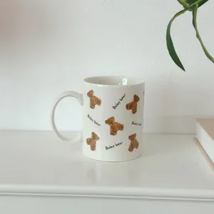 Close-up of white ceramic mug featuring hand-drawn baby bear pattern and handle detail