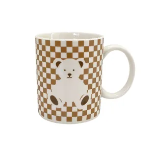 Ceramic checkered mug with cute brown bear print and ergonomic handle on white background