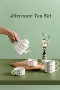 Macro detail of matte white ceramic teapot pouring tea into a relief pattern cup