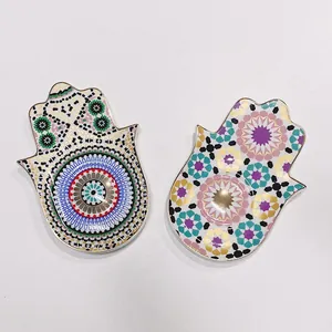 Vista macro di vassoi per gioielli Hamsa in ceramica con bordo dorato e motivi etnici