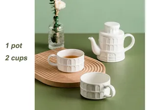 Detail of white ceramic tea set with architectural relief featuring one pot and two cups