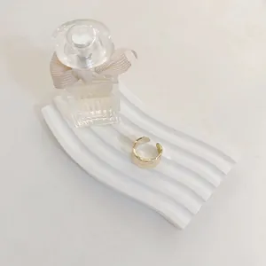 Gold open adjustable ring with irregular hammered texture on white plaster board