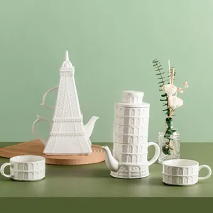 White ceramic Eiffel Tower teapot and pillar style cup set on a wooden tray