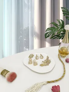 Detail of luxury gold jewelry set with pearls and brooch on aesthetic ceramic tray
