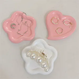 Flat lay of pink heart and flower shaped ceramic jewelry trays with glossy finish