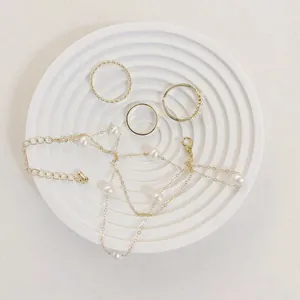 Flat lay of gold jewelry set with pearls on a white textured resin display tray