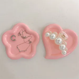 Flat lay of pink flower and heart resin jewelry trays with necklaces and hair claw