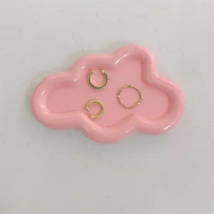 Three-piece gold ear cuff and ring set displayed on a pink cloud-shaped resin jewelry tray