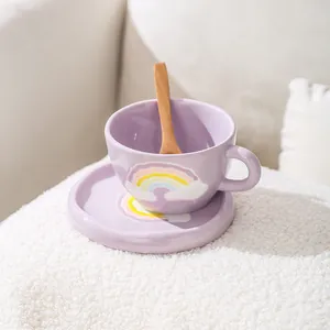 Detail view of purple ceramic coffee cup with rainbow patterns, saucer, and wooden spoon