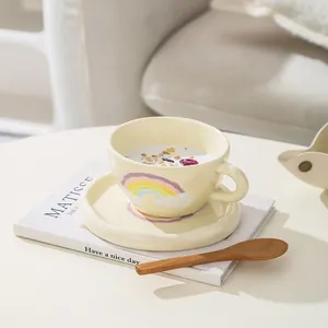 Detail of hand-painted rainbow ceramic cup with matching saucer and wooden spoon
