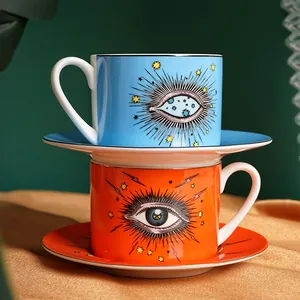 Blue and orange ceramic coffee cup and saucer set with eye motif and gold rim detailing