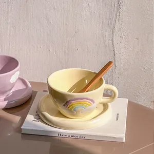Detail of cream yellow ceramic cup with rainbow relief and a wooden stirring spoon