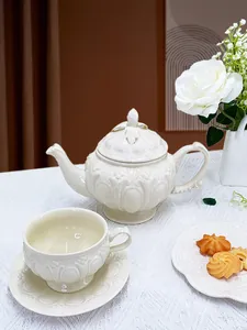 Détail d'un service à thé britannique en céramique gaufrée sur nappe en dentelle