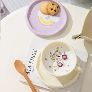 Top-down view of cream ceramic coffee cup and saucer set with a hand-painted rainbow plate