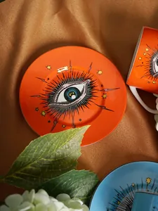 Detailed top view of ceramic cup and saucer set with artistic orange star eye pattern