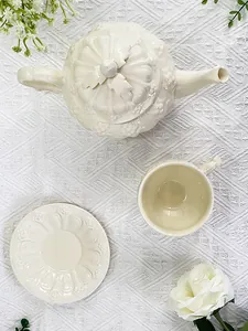 Vue de dessus du service à thé en céramique à relief sur nappe en dentelle