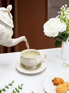 Détail d'une théière en céramique avec relief versant du thé dans une tasse assortie