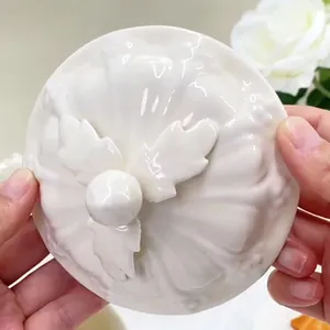 Détail d'un couvercle en céramique blanche avec poignée en feuille et texture côtelée