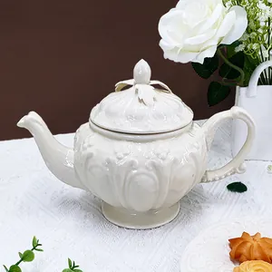 Théière vintage en céramique avec reliefs floraux sur une nappe en dentelle blanche