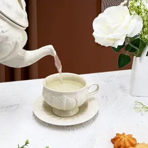Service à thé vintage en céramique avec reliefs sur une nappe en dentelle blanche