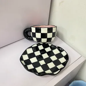 Détail d'un ensemble tasse à café et soucoupe en céramique au motif à damier noir