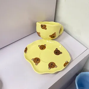 Détail de la tasse à café en céramique jaune avec soucoupe ondulée et motif d'ours