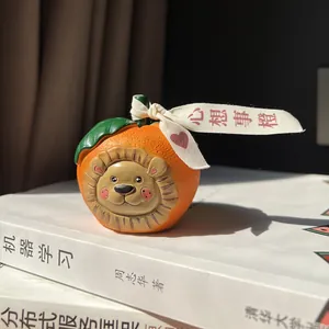 Detailed view of handmade resin lion orange figurine with a festive ribbon on books