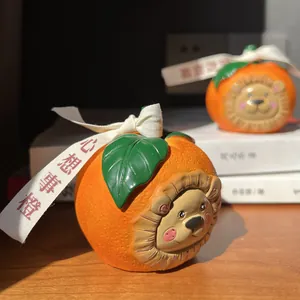 Detail of orange resin ornaments with cartoon lion heads and fabric ribbons on white books