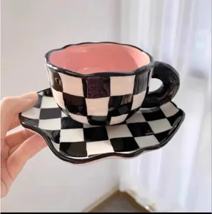 Détail d'une tasse à café en céramique à carreaux avec glaçure intérieure rose et soucoupe