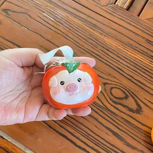 Close-up of handmade resin persimmon pendant with cute cartoon pig face detail