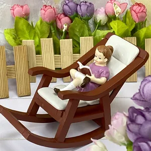 Detail of miniature resin girl figure reading on a rocking chair for fairy garden decor