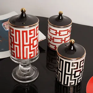 Pots à bougies géométriques en céramique avec détails dorés sur fond noir réfléchissant
