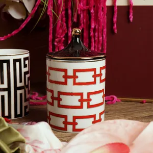 Vue détaillée du pot à bougie en céramique à motif de chaîne rouge et poignée dorée