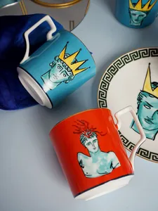 Dettaglio di tazze in ceramica di lusso e piatto con motivi greci e bordi dorati