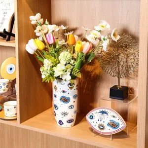 Witte keramische vaas met boze oog en decoratief dienblad op modern houten rek