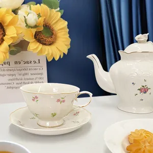 Close-up of elegant floral ceramic tea set with gold trim and scalloped edges