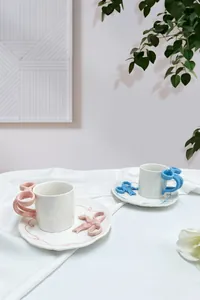 Dettaglio del set da caffè in ceramica con manico a fiocco fatto a mano e piattino colorato