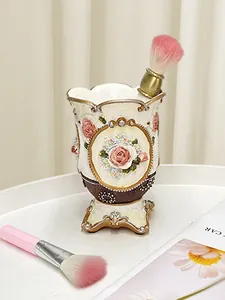 Dettaglio rilievo rosa vintage su porta pennelli trucco avorio con accenti oro