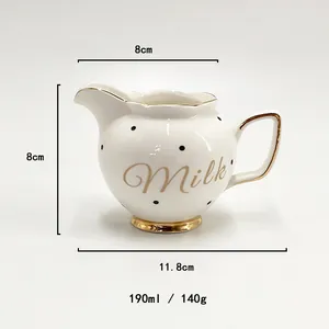 Detailed view of white ceramic milk pitcher with black polka dots and gold trim handle